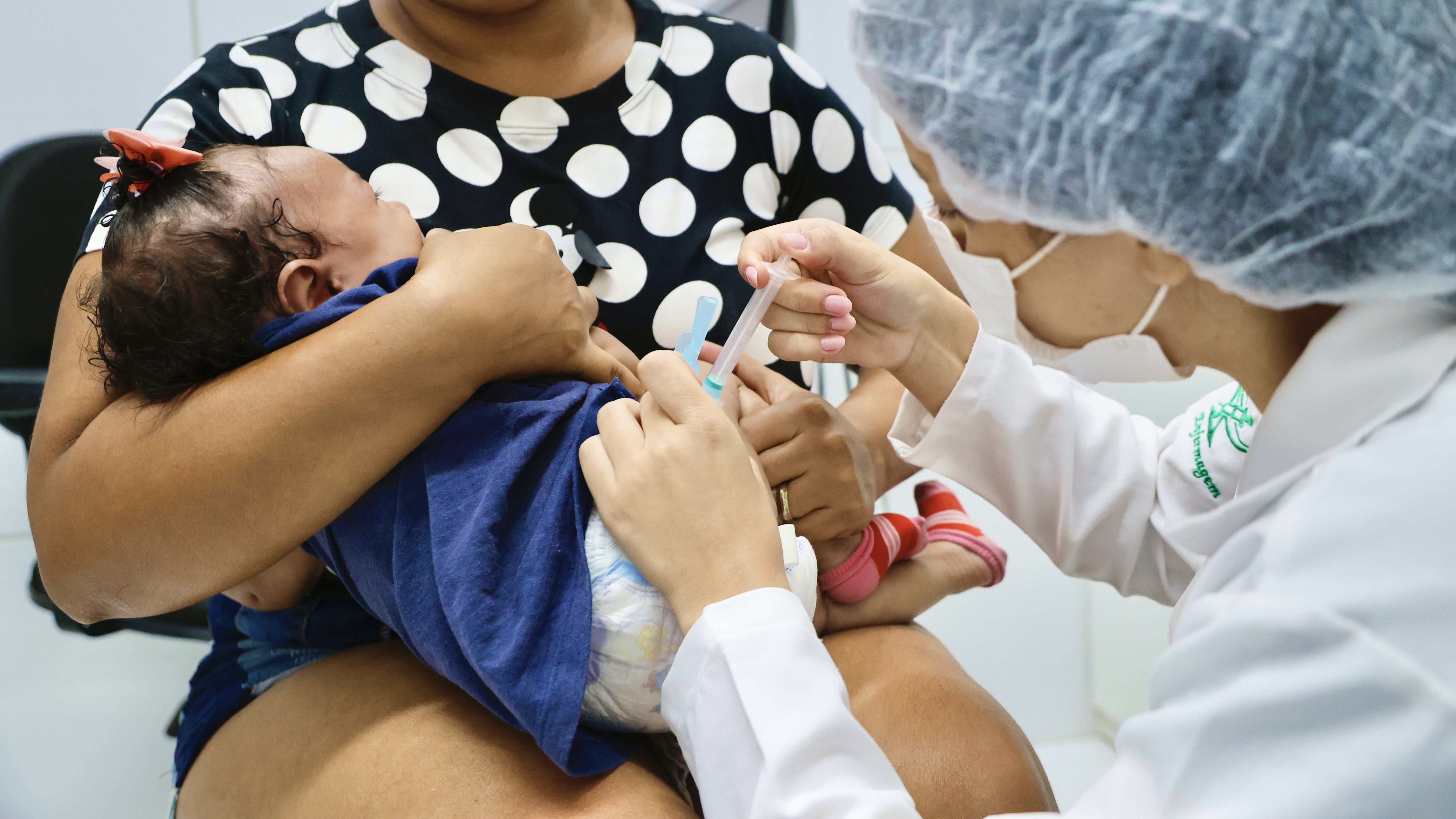 enfermeira vacinando uma bebê que está no colo da mãe